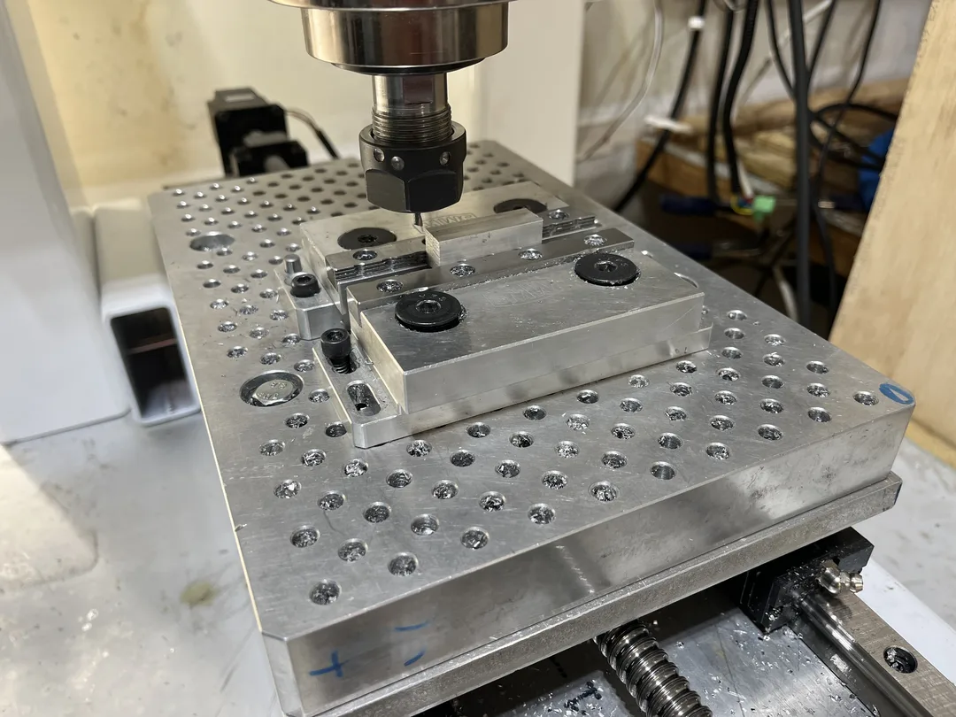 CNC mill table with cutter about to cut aluminum block in vise.